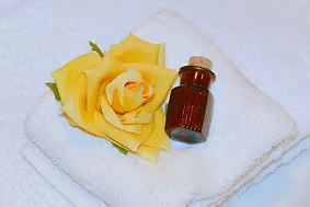 Ambiente Bild mit einer gelben Rose auf einem weißen Handtuch und einem Elexierfläschen.